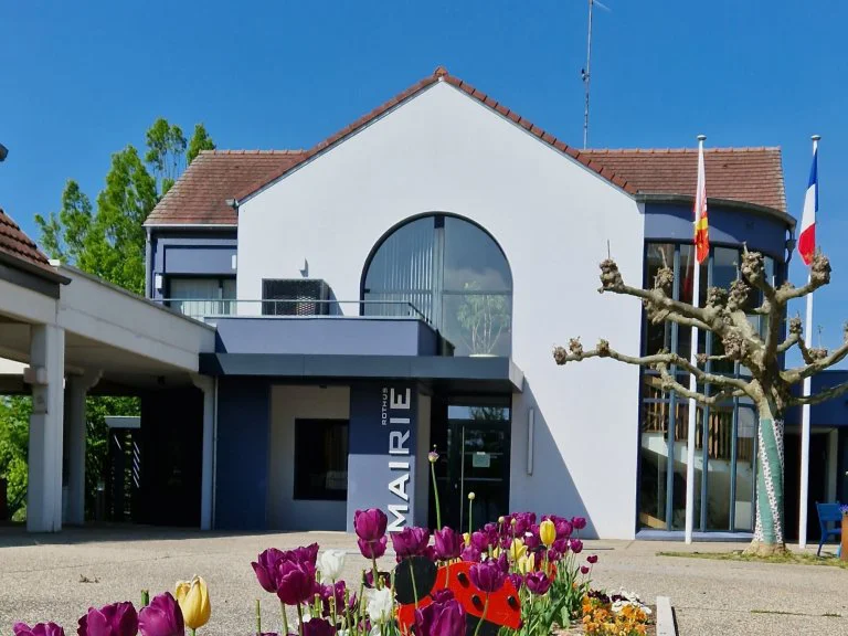 The Mairie de Chalampé in spring, with tulips in bloom and the French flag